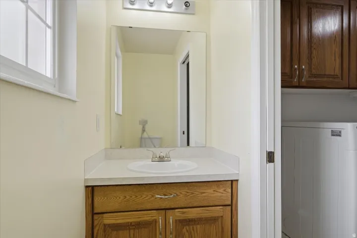 Bathroom vanity featuring a wood-finish cabinet, white countertop, and integrated sink