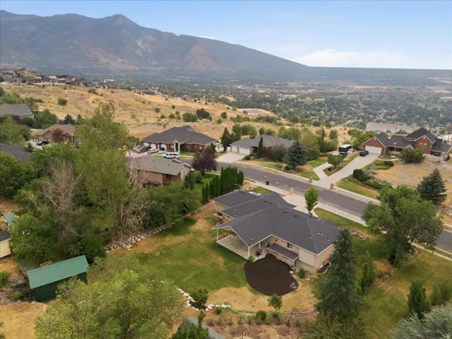 Aerial perspective showcasing a single-family residence with a dark shingle roof and a covered patio