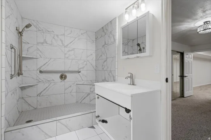 Bathroom featuring a walk-in shower with marble-look tile, integrated bench seating, and brushed nickel fixtures