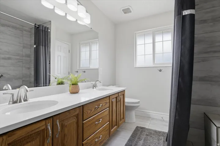 Bathroom featuring a dual-sink vanity with wood-finish cabinetry, white countertop, and brushed nickel fixtures