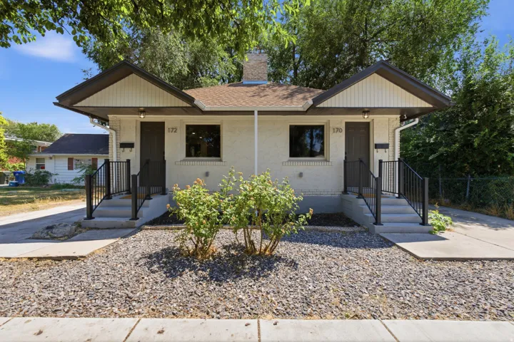 Duplex exterior featuring two distinct entryways with concrete steps and black metal railings