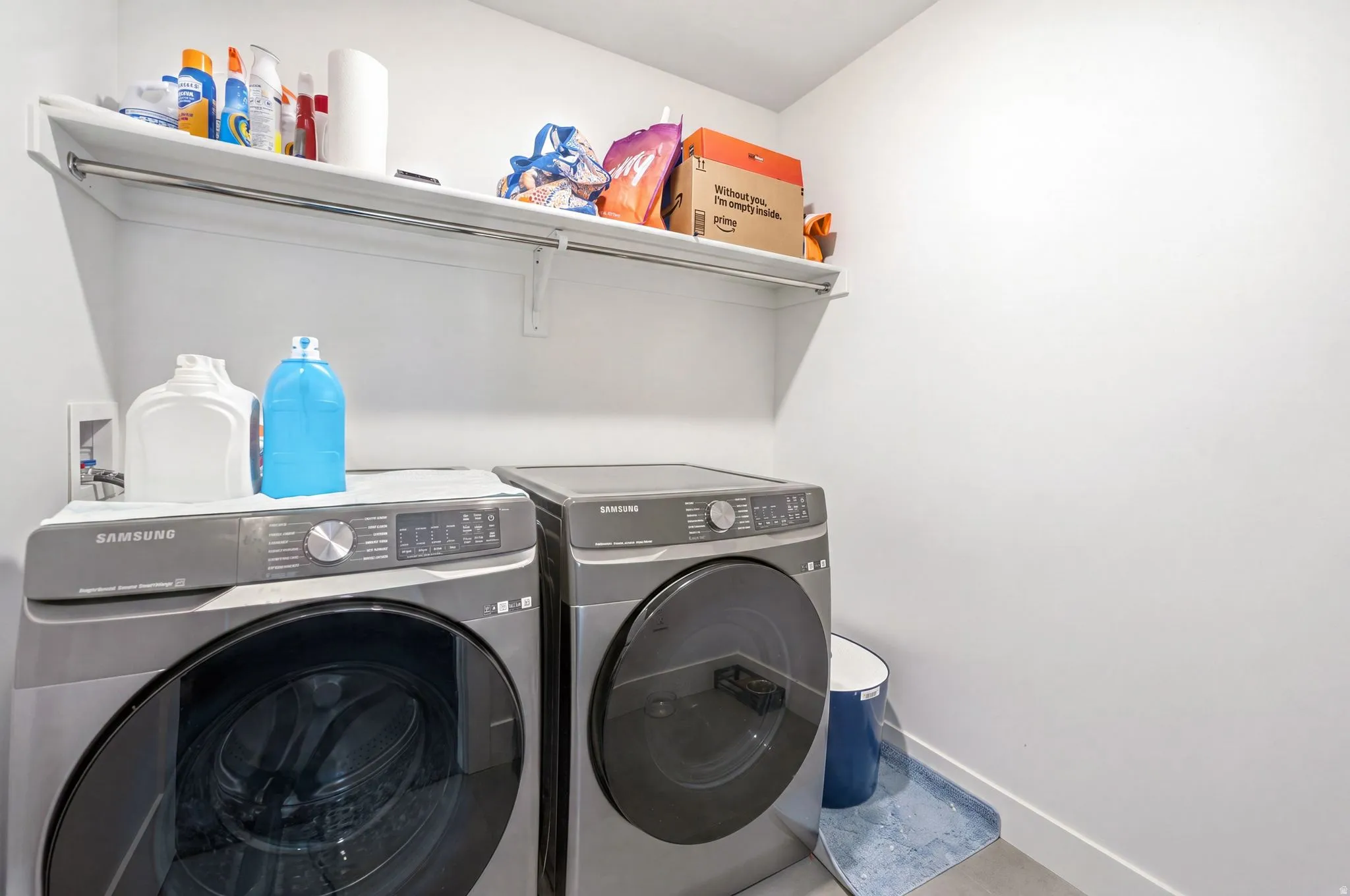 Dedicated laundry area featuring a white wall shelf, a hanging rod, and light-colored flooring