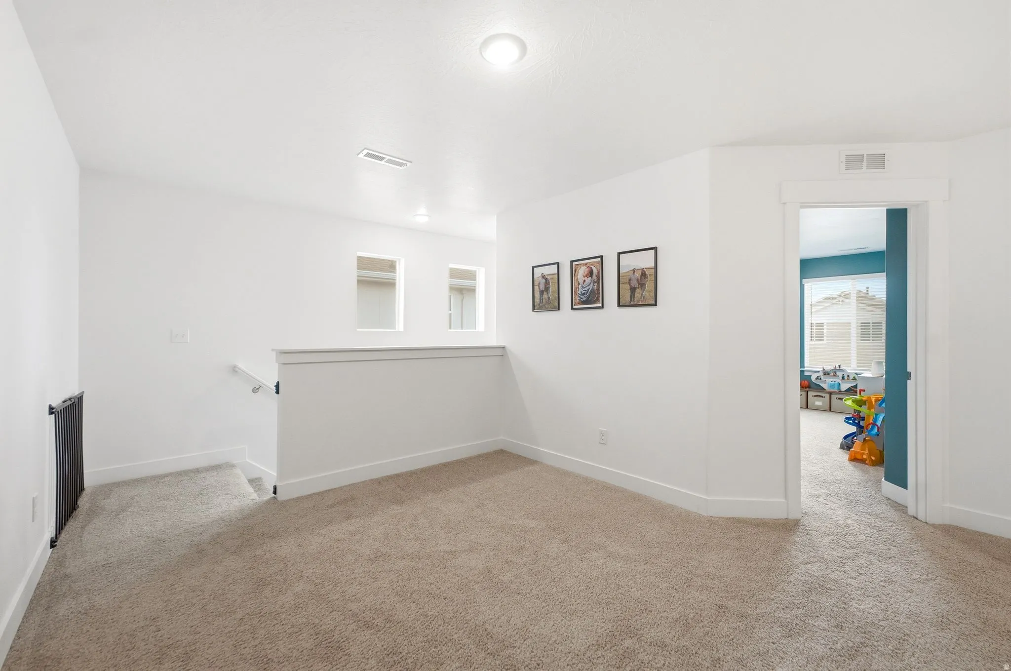 Carpeted landing area featuring a white railing, recessed lighting, and a doorway with white trim