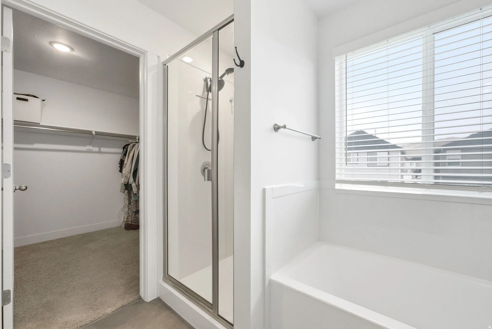 Contemporary bathroom featuring a glass-enclosed shower, white bathtub, and a window with blinds