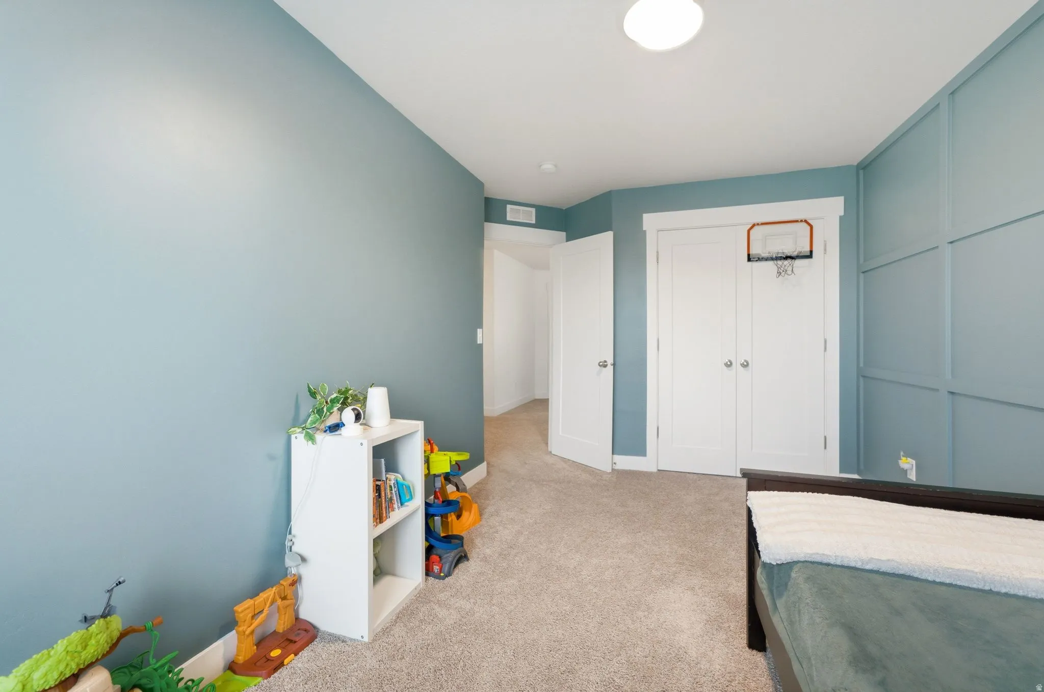 Bedroom featuring a paneled accent wall, neutral carpeting, and a white flush-mount ceiling light