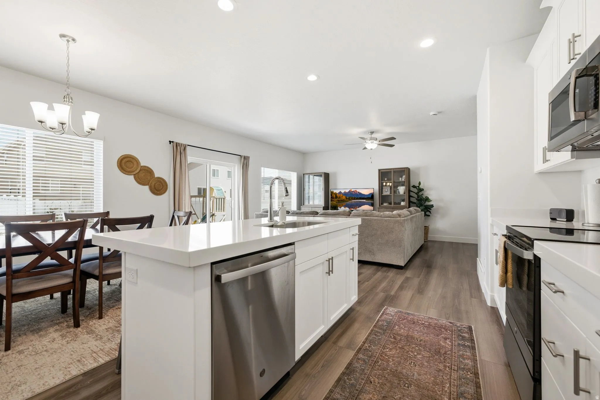 Kitchen island featuring a stainless steel dishwasher, white cabinetry, and a light-toned countertop
