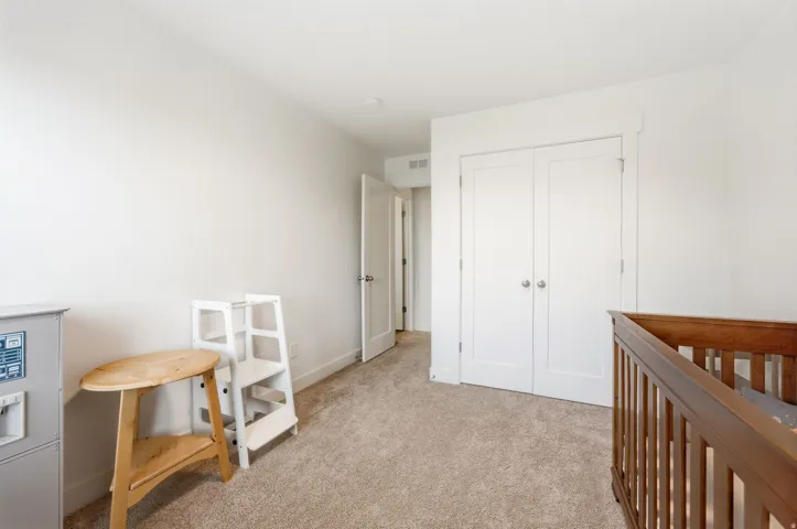 Carpeted room featuring light-toned walls, white trim, and a white double-door closet with round silver hardware