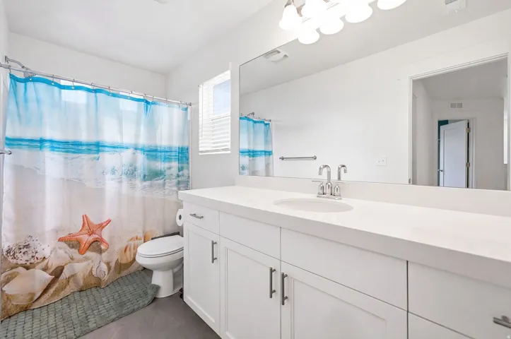 Bathroom featuring a vanity with an integrated sink, white cabinetry, and a large mirror