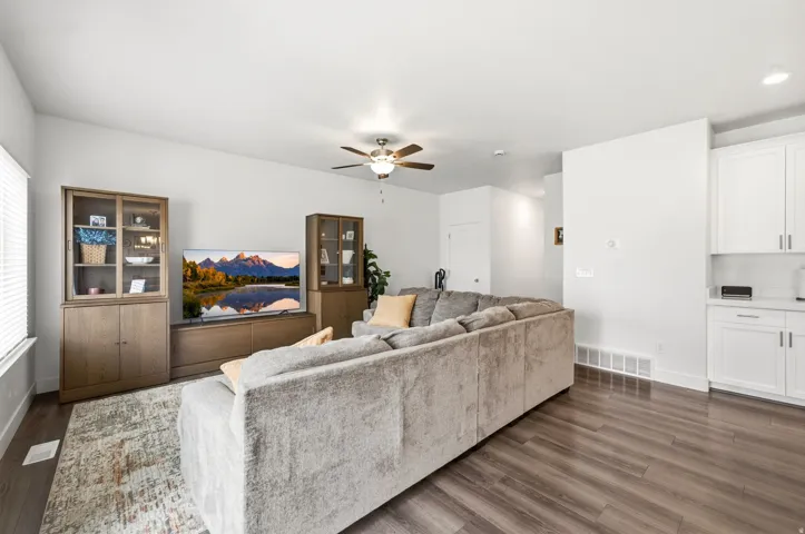 Open-concept living space featuring wood-finish flooring, a ceiling fan, and white painted walls