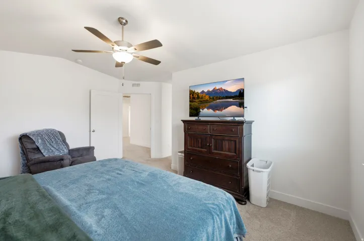 Carpeted room featuring a ceiling fan with integrated lighting, white walls, and a white door with a round silver handle