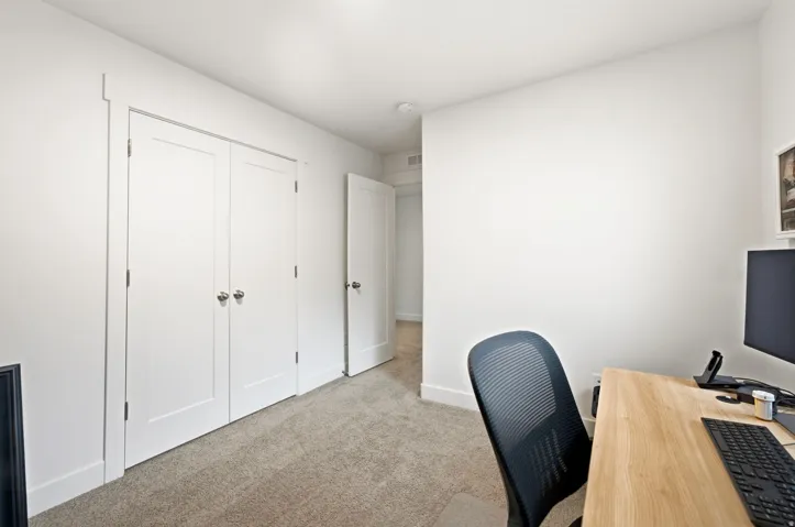 Neutral toned carpeted room featuring white walls and a double-door closet