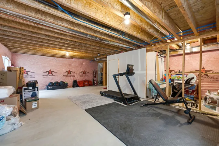 Unfinished basement featuring exposed wood joists, concrete flooring, and partial wall framing for future development