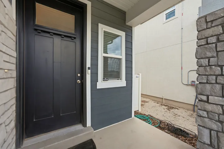 Modern paneled entry door with transom window, complemented by deep gray horizontal siding