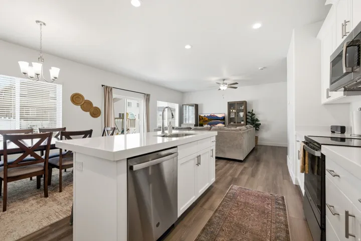 Kitchen island featuring a stainless steel dishwasher, white cabinetry, and a light-toned countertop