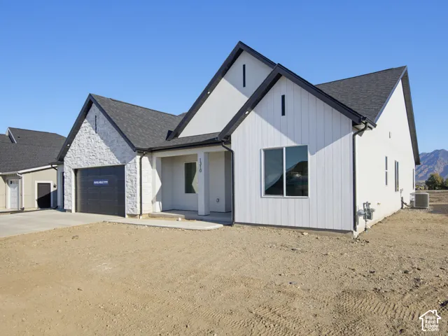 Modern exterior featuring board-and-batten siding, stone veneer accents, high-pitched rooflines, and a covered front entryway