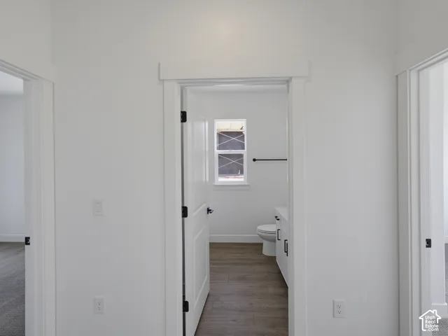Interior doorway featuring white casing, solid-core doors with matte black hardware, wood-finish flooring, and a single-hung window