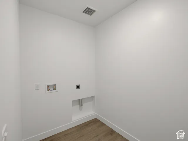 Utility area featuring wood-finish flooring and dedicated water, electrical, and drainage hookups