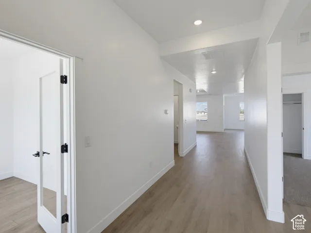 Interior hallway with wood-finish flooring, recessed lighting, and white interior doors featuring black hardware