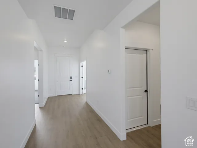 Entryway featuring wood-finish flooring, white panel doors, matte black hardware, and recessed lighting