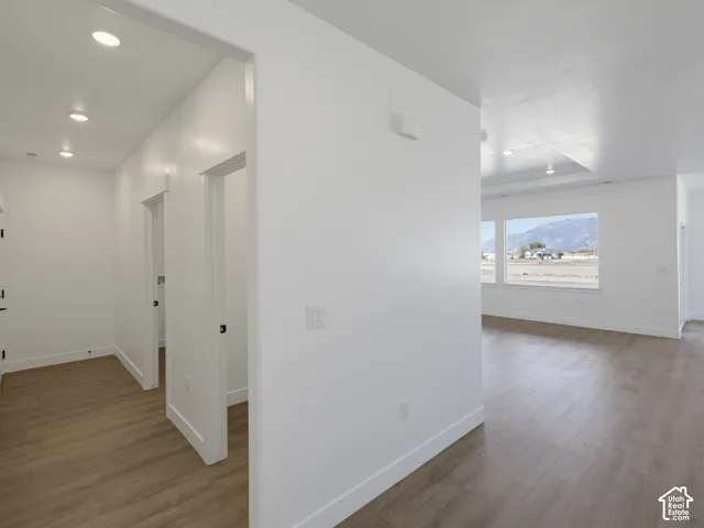 Interior space featuring wood-finish flooring, recessed lighting, a recessed ceiling detail, and large windows with mountain scenery