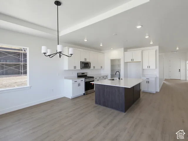 Kitchen featuring white shaker-style cabinetry, a contrasting center island with a stone-surface countertop, recessed lighting, and wood-finish flooring