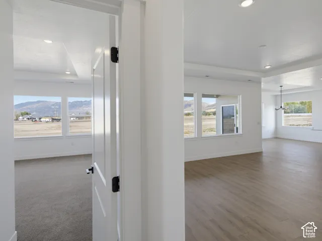 Interior featuring tray ceilings, recessed lighting, wood-finish flooring, and large windows with mountain scenery