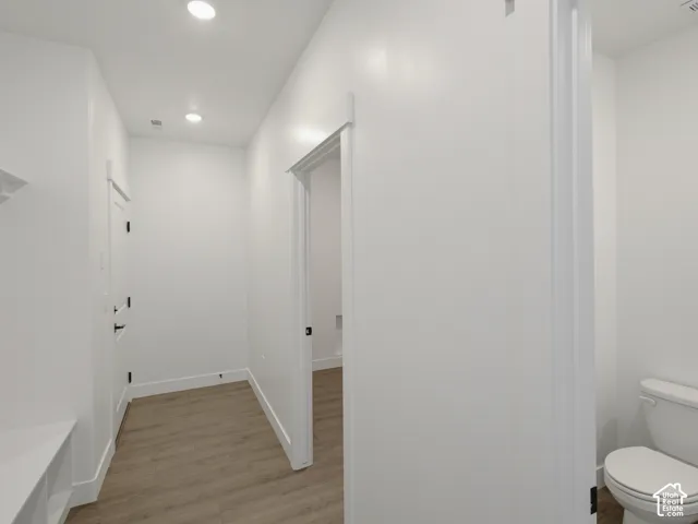 Wood-finish flooring, recessed lighting, and white interior doors with matte black hardware