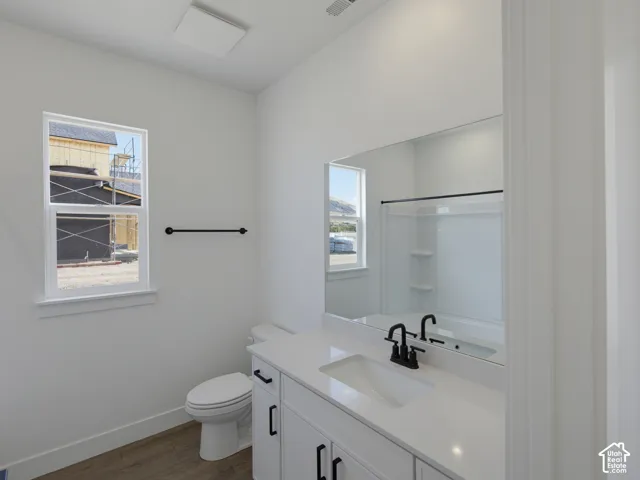 White cabinetry with matte black hardware, stone-finish countertop, undermount sink, matte black faucet, and wood-finish flooring