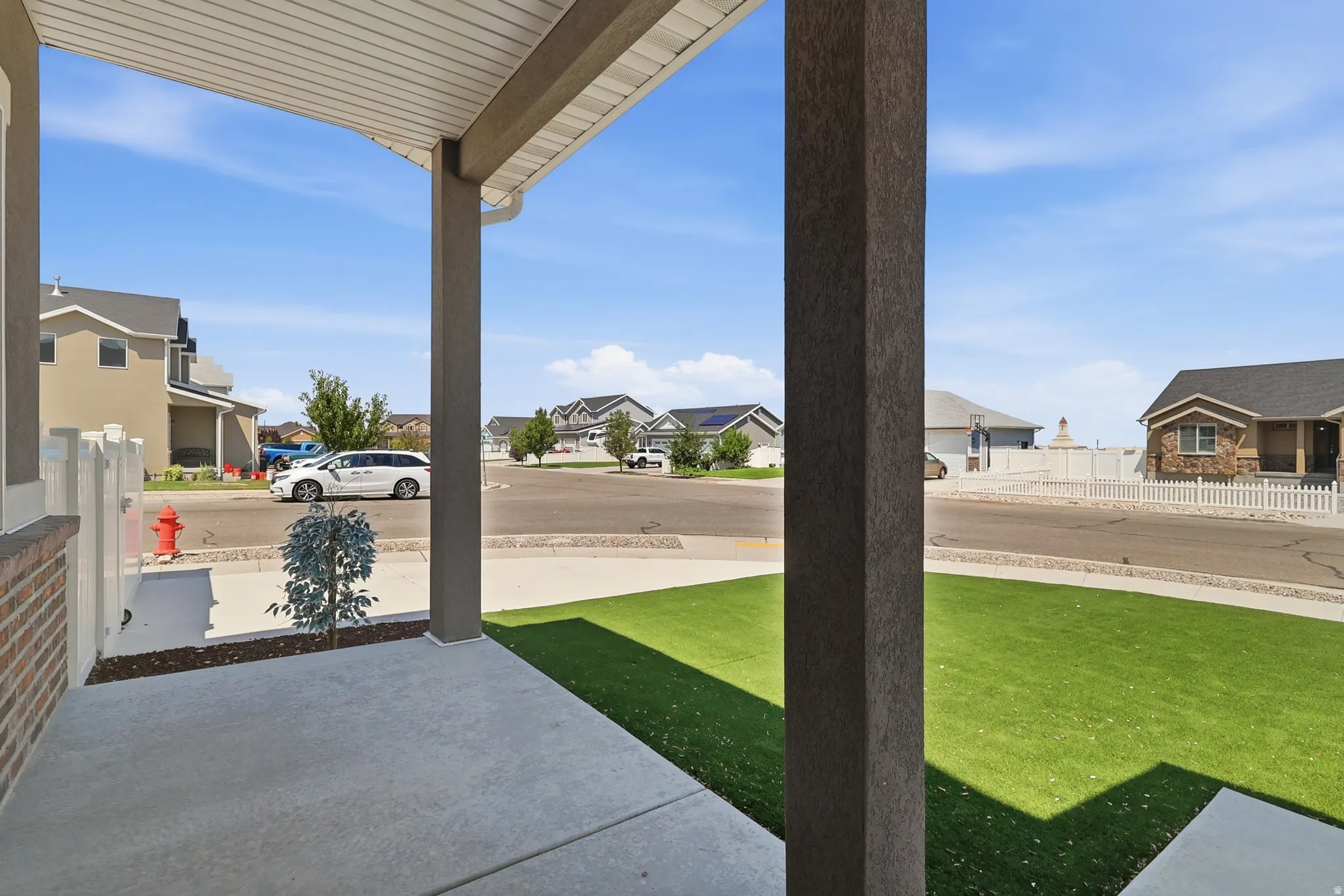 Covered front porch with concrete flooring and stucco-finished columns