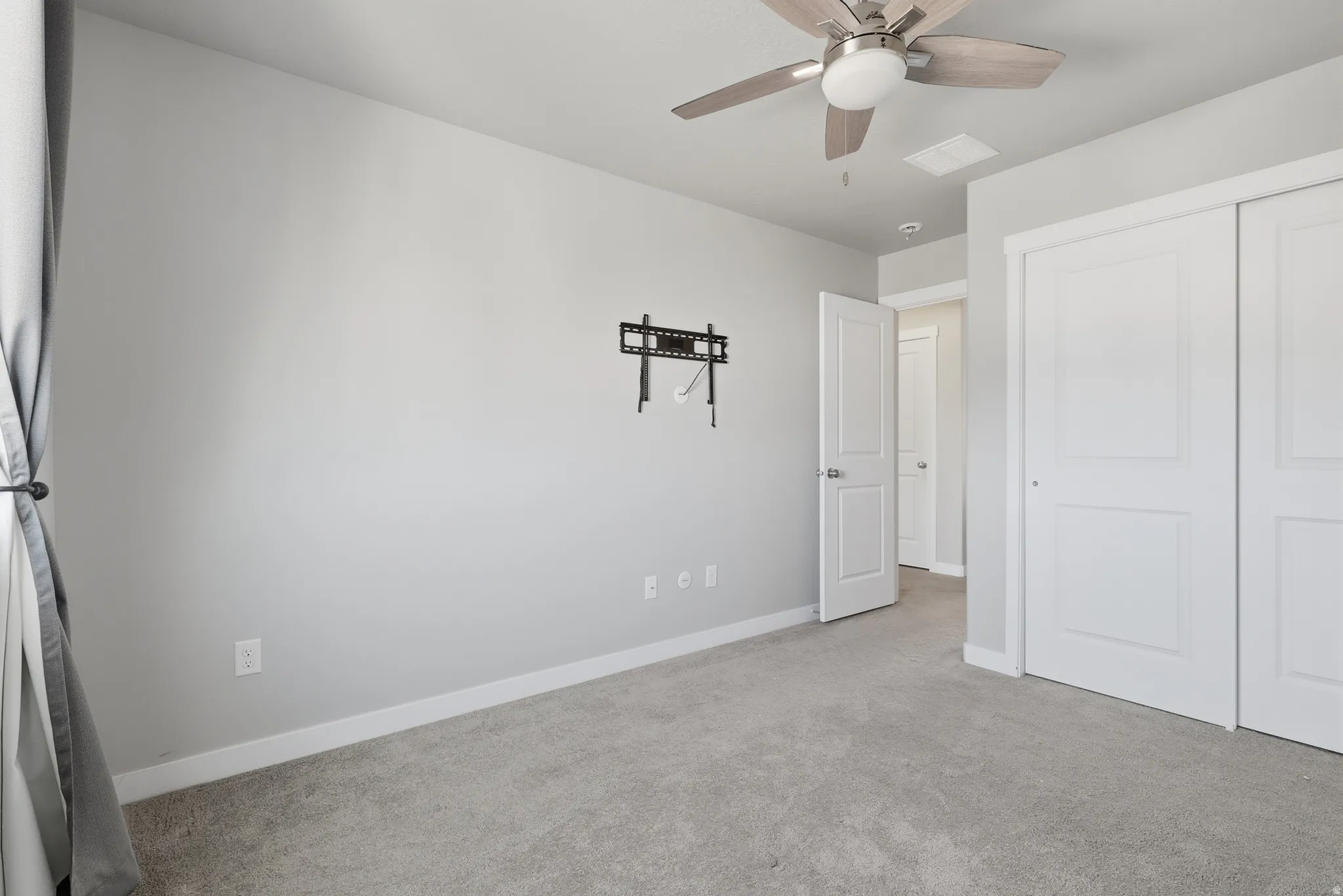 Room featuring light gray walls, gray carpeting, and white baseboards