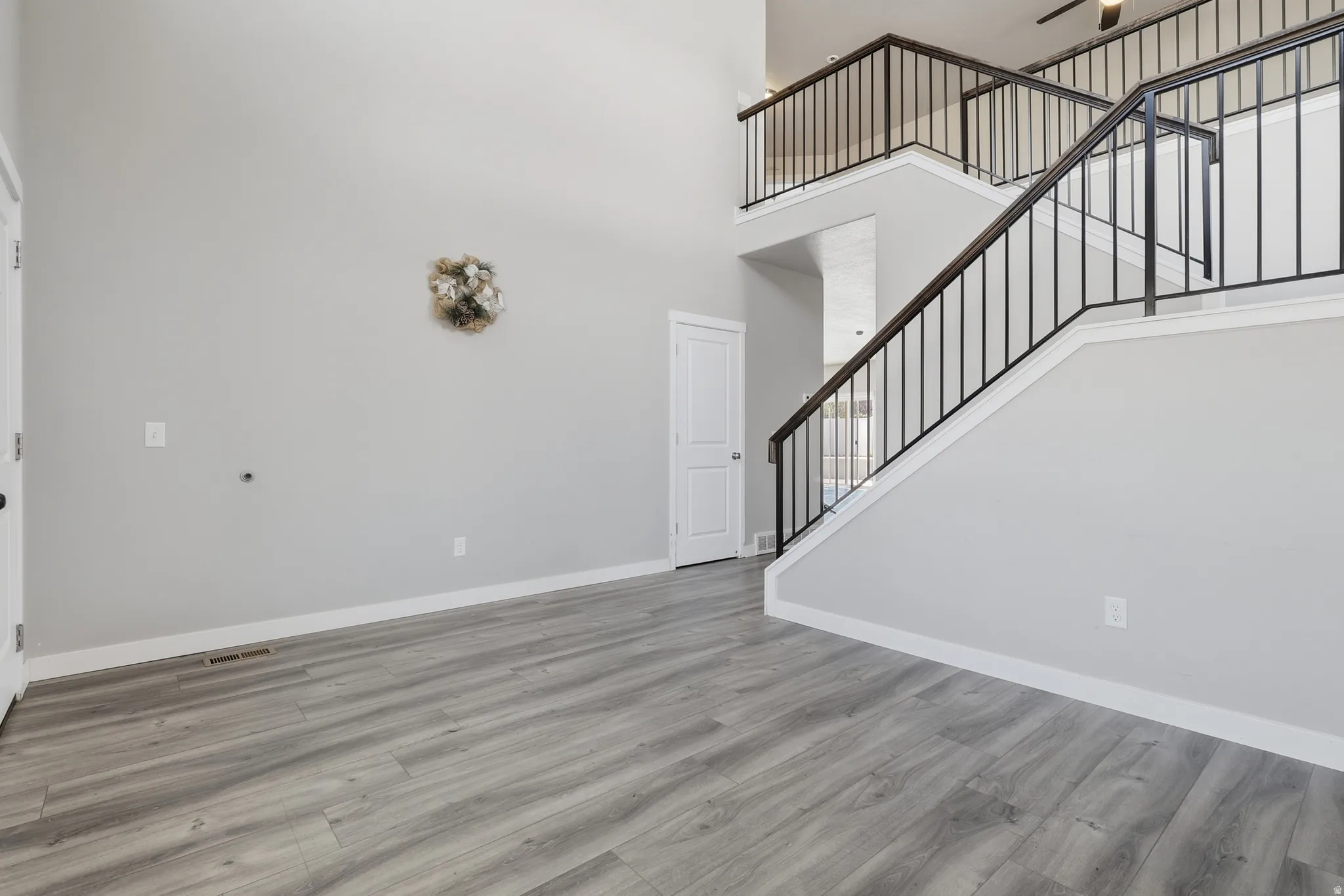 Two-story entry featuring light gray walls, wood-finish flooring, and a staircase with dark metal railings