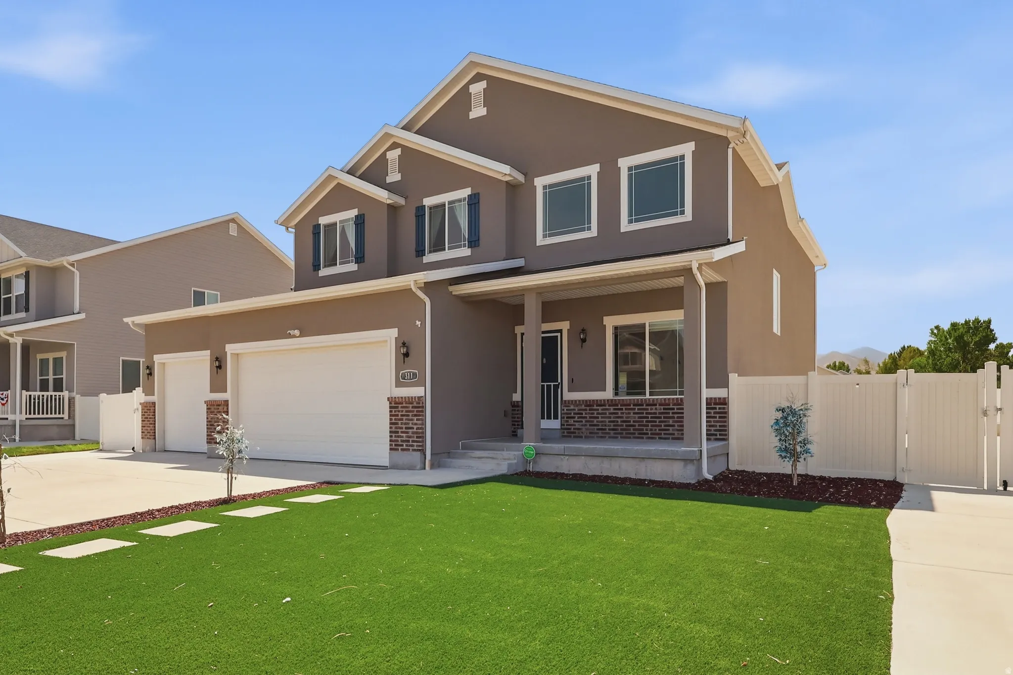 Two-story stucco exterior featuring a covered front porch, a two-car garage, and a single-car garage