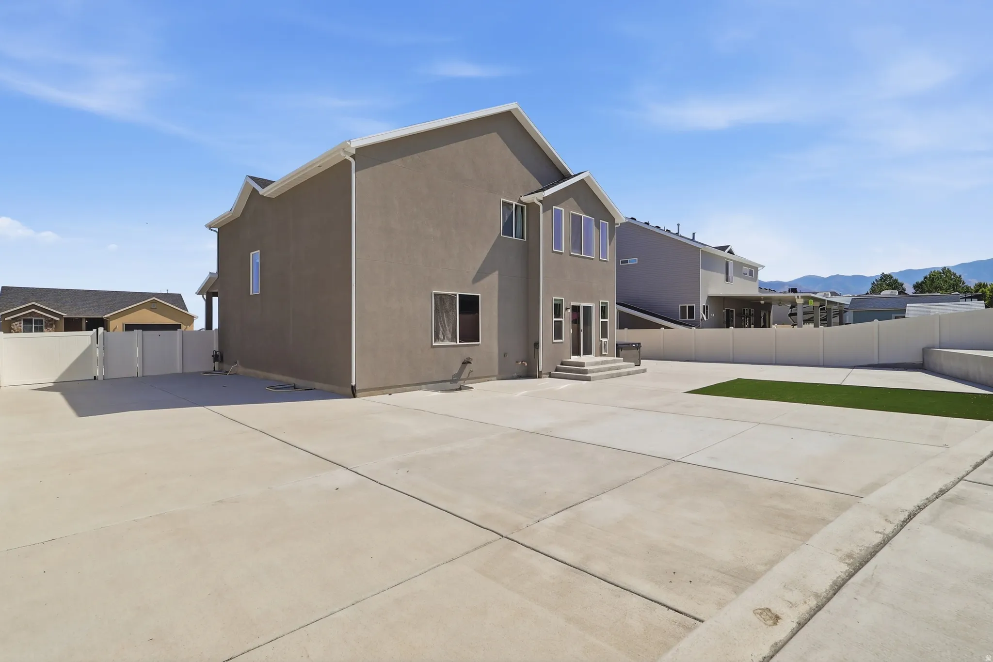 Expansive concrete patio area with a rectangular artificial turf section