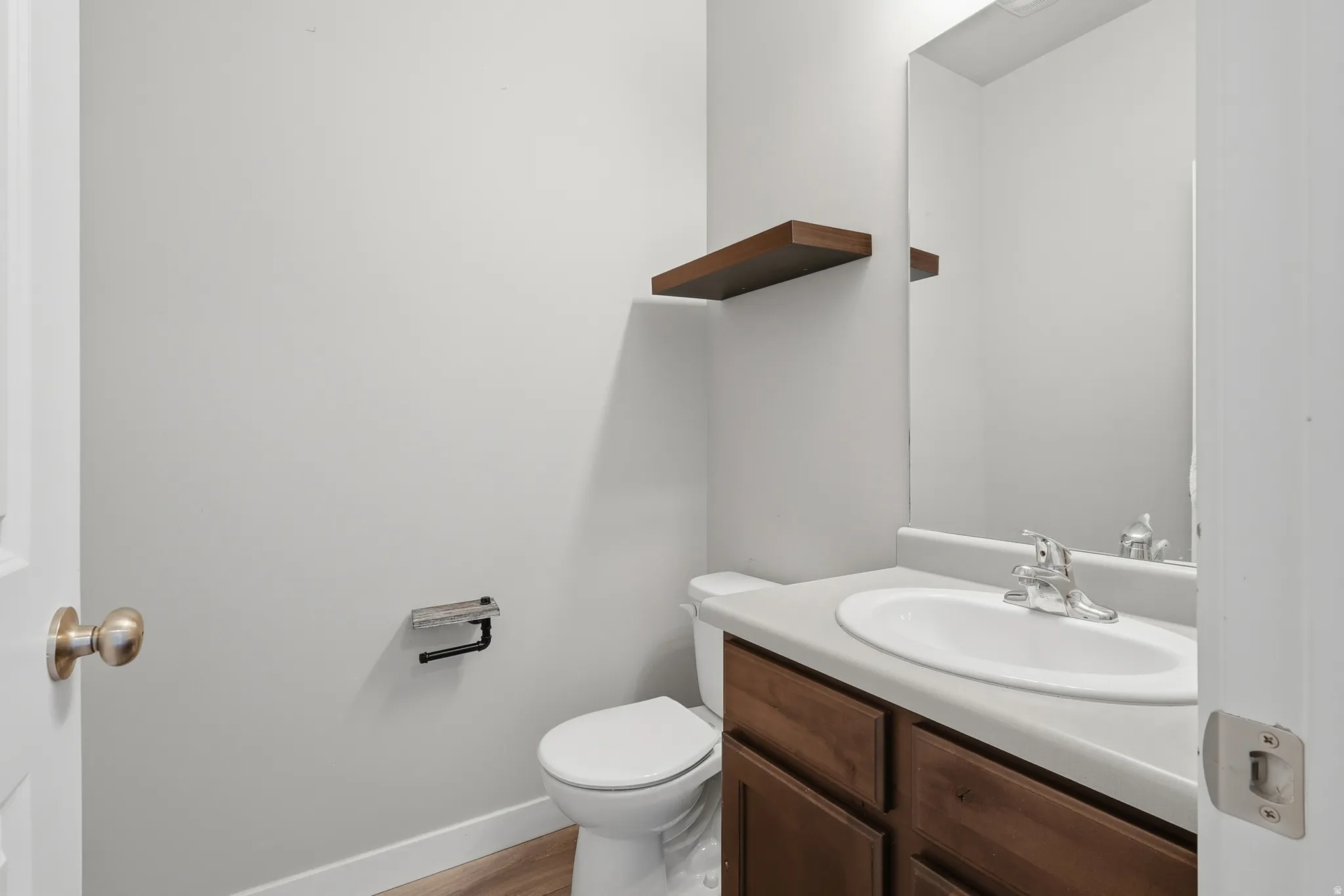 Vanity with wood-finish cabinetry, integrated sink, and laminate countertop