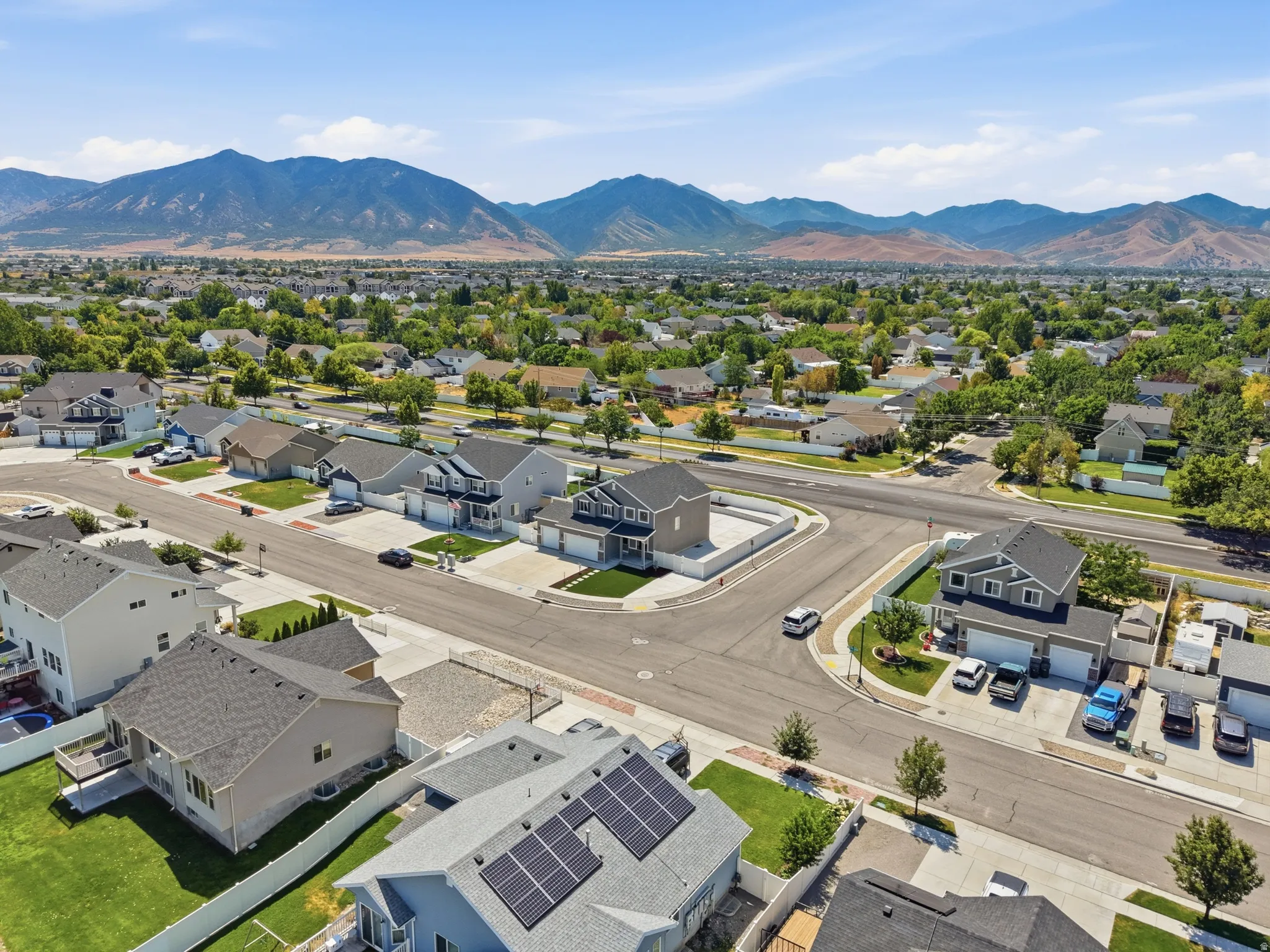 Aerial overview showcasing a residential neighborhood with mountain backdrops, mature trees, and varying architectural styles