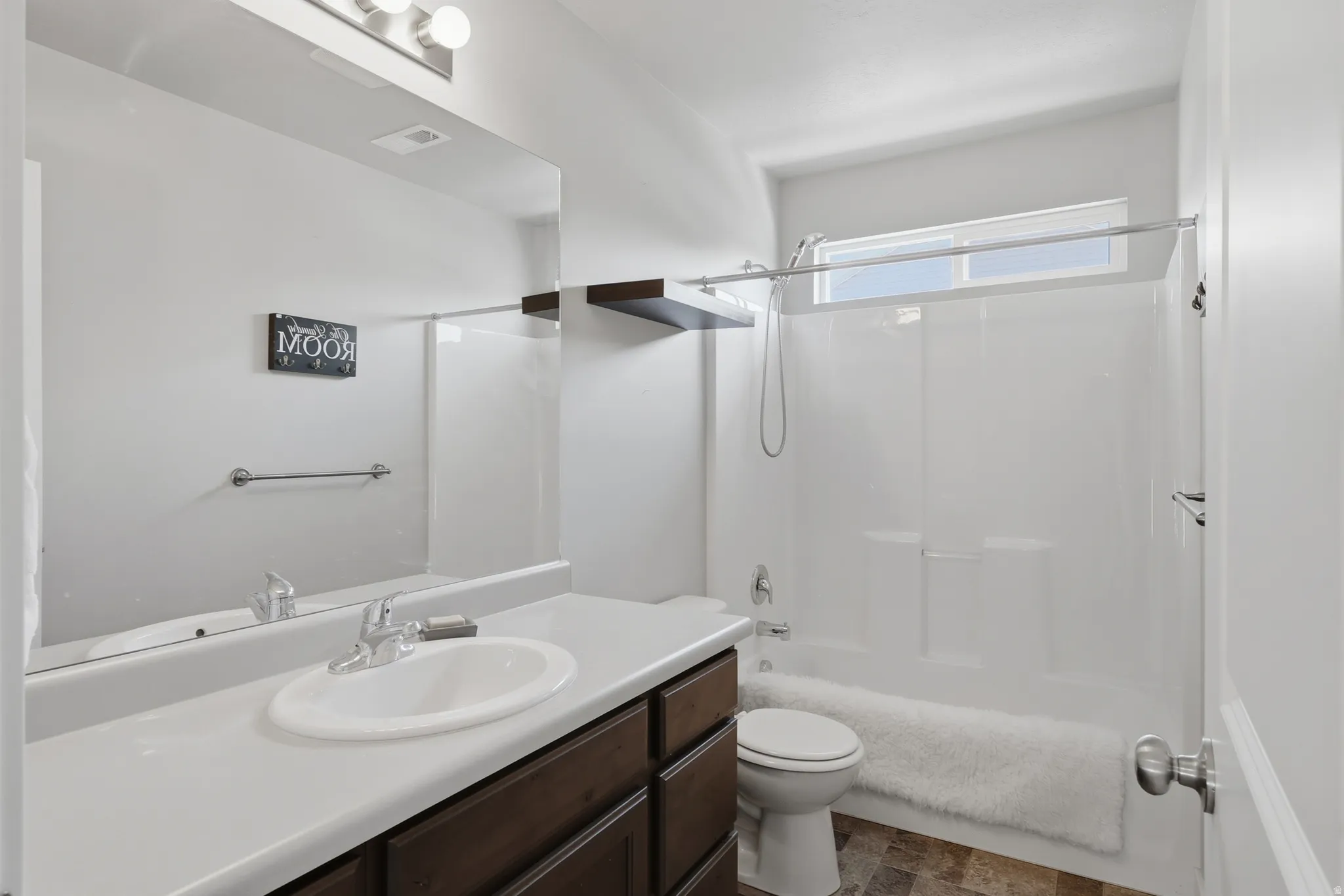 Full bathroom featuring a single vanity with a white countertop, dark wood-finish cabinetry, and a white oval sink