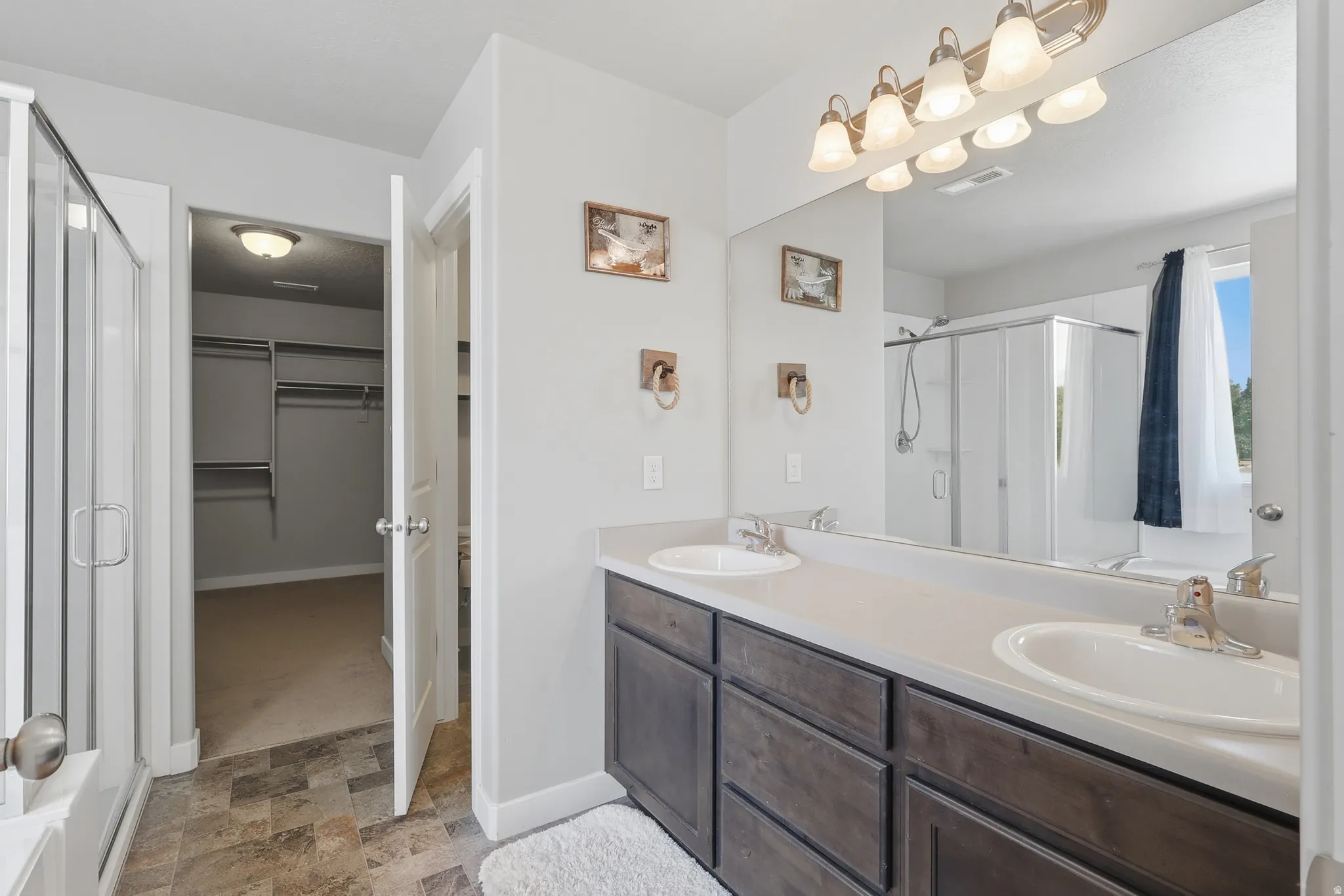 Bathroom featuring a double vanity with ample counter space, rich wood-finish cabinetry, and individual sinks