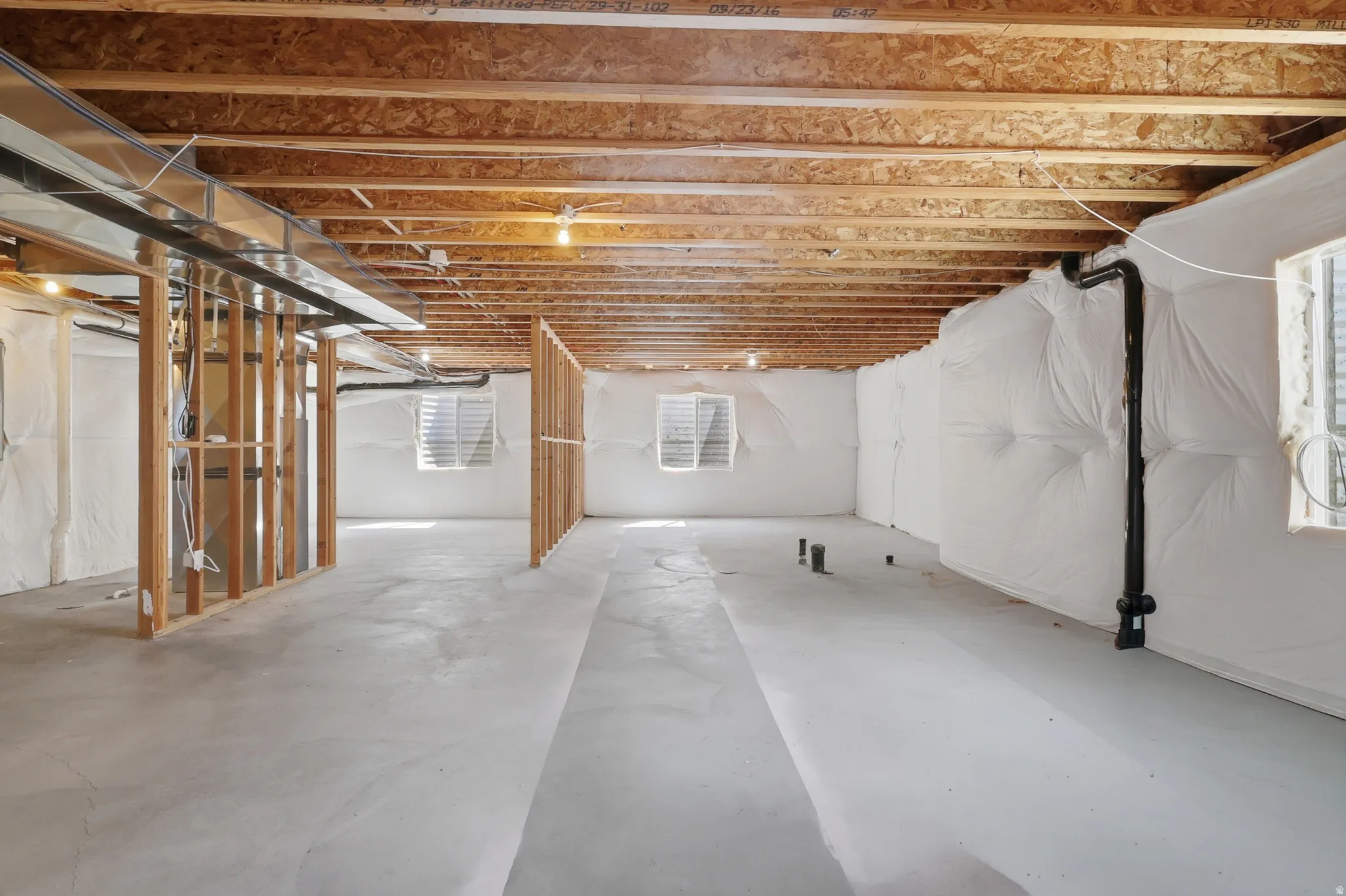 Unfinished basement featuring exposed wood joists, concrete flooring, and framed partition walls