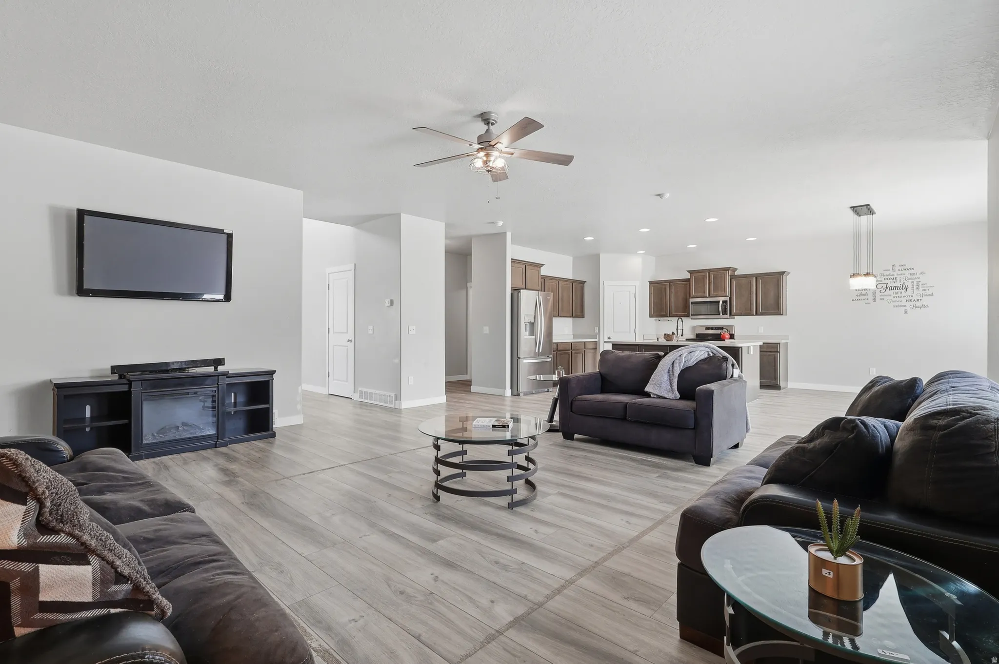 Open-concept living area featuring wood-finish flooring, a ceiling fan, and recessed lighting