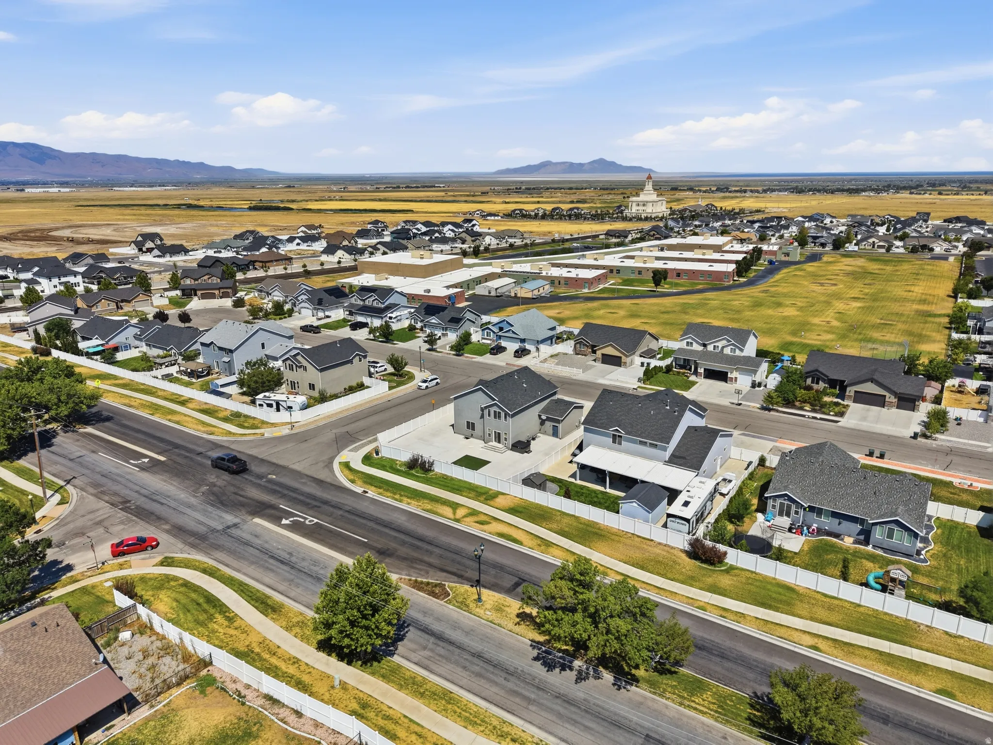 Aerial perspective showcasing a residential neighborhood with varied architectural styles and surrounding open fields