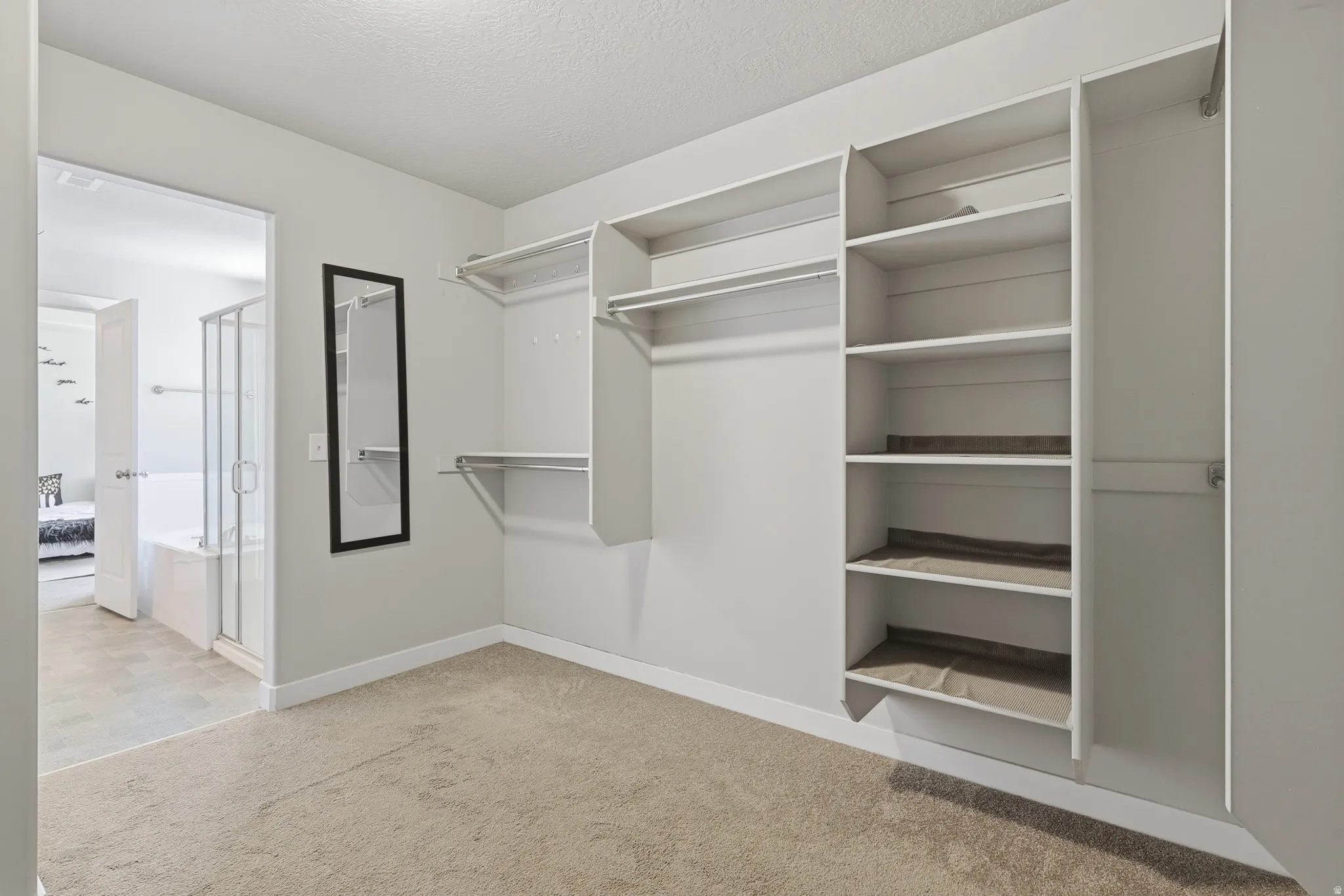 Walk-in closet with built-in shelving, multiple hanging rods, and neutral-toned carpeting