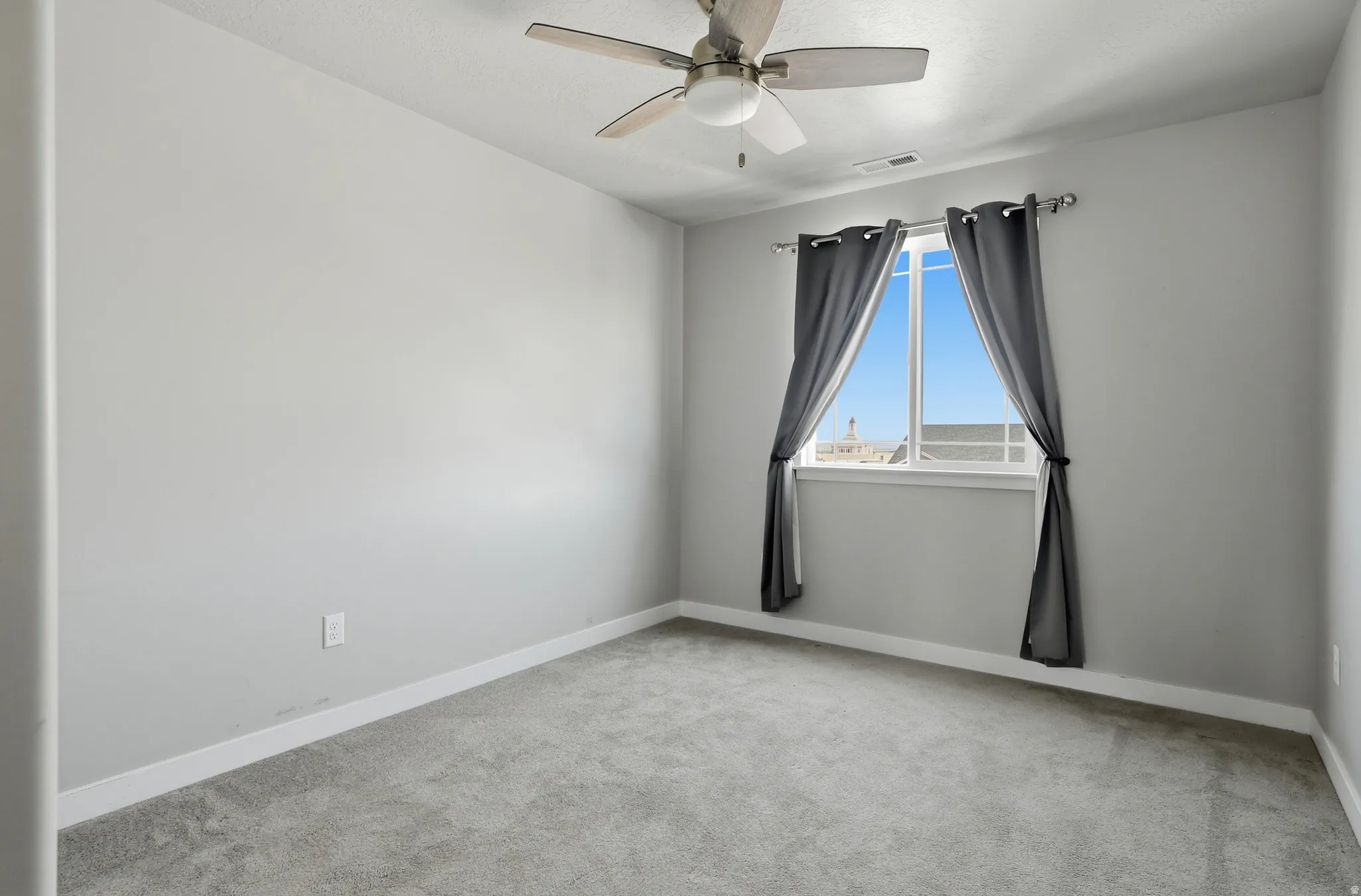 Carpeted room featuring a ceiling fan with integrated lighting, a single window, and light gray wall finishes