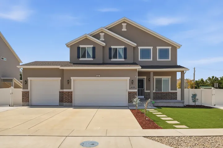 Two-story residence featuring a stucco exterior with brick accents and white trim