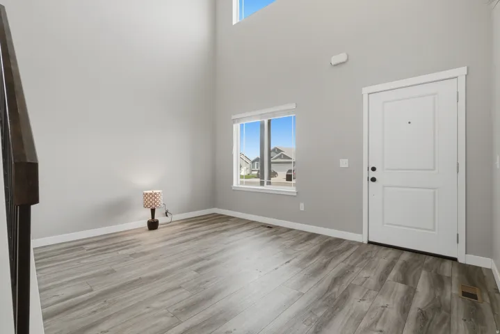 Entryway featuring high ceilings, wood-finish flooring, a contemporary white entry door, and a prominent window