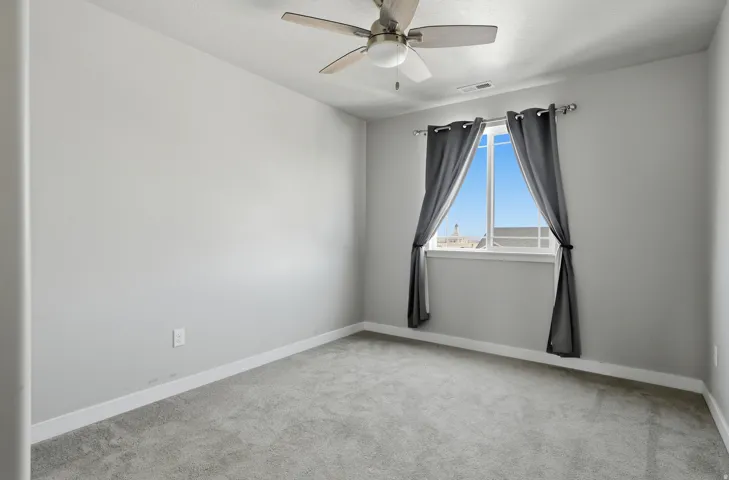Carpeted room featuring a ceiling fan with integrated lighting, a single window, and light gray wall finishes