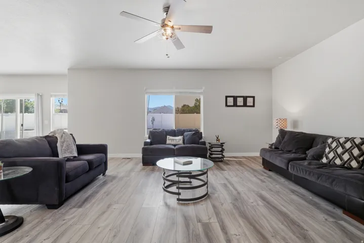 Spacious living area featuring wood-finish flooring and a ceiling fan with integrated lighting