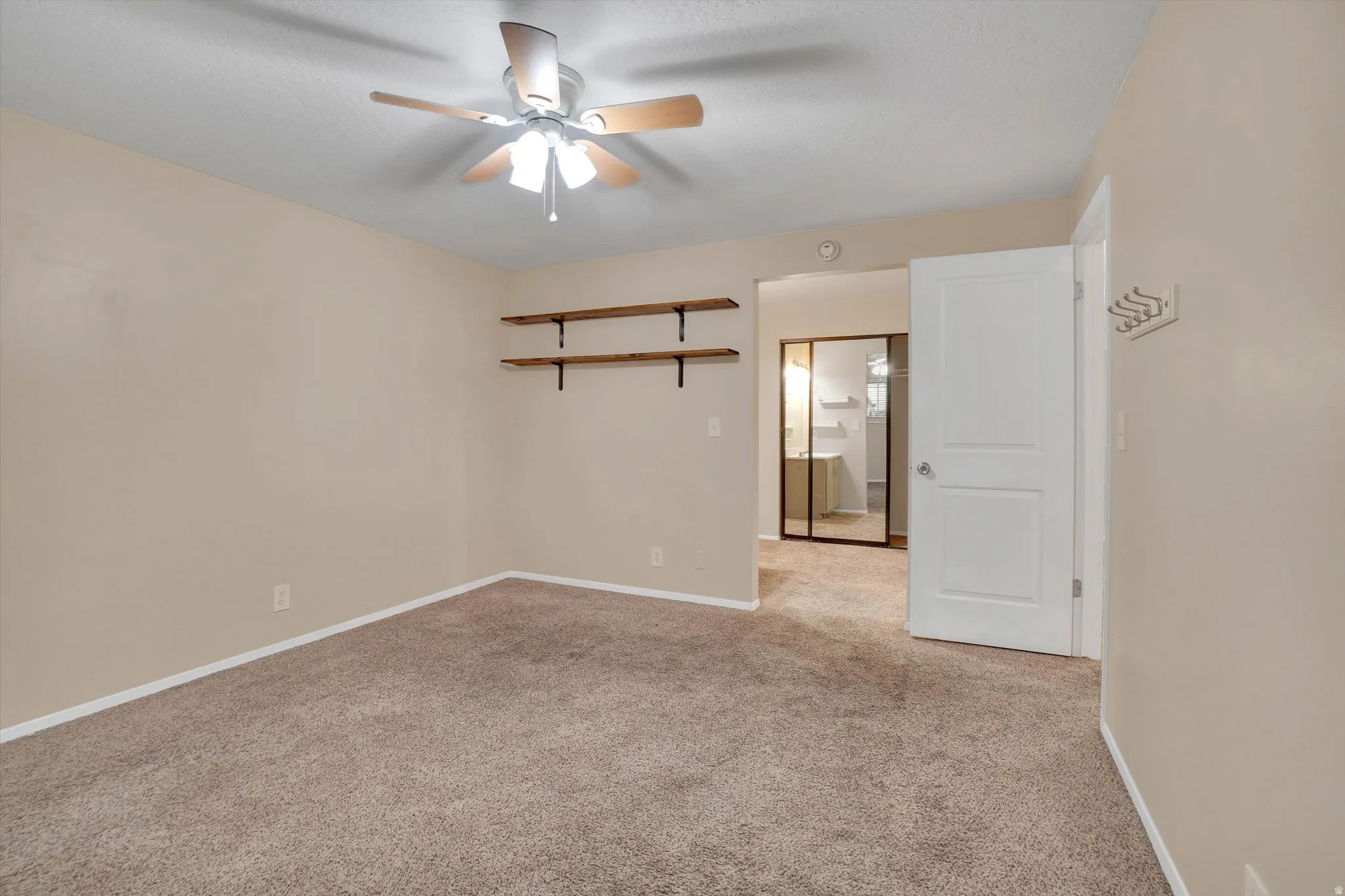 Master bedroom has Carpeted room with a ceiling fan, neutral wall paint, and built-in shelving