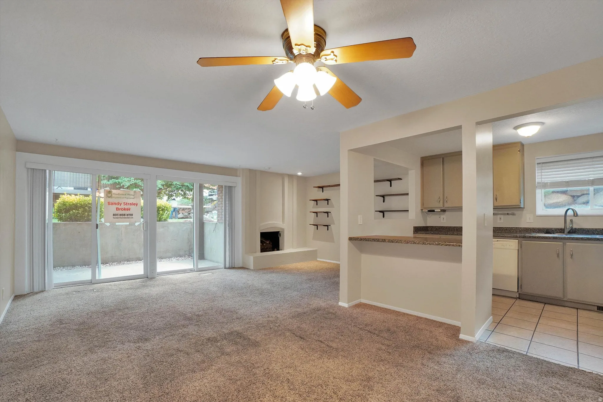 Living area featuring carpet flooring, a ceiling fan with light, and a fireplace with a hearth