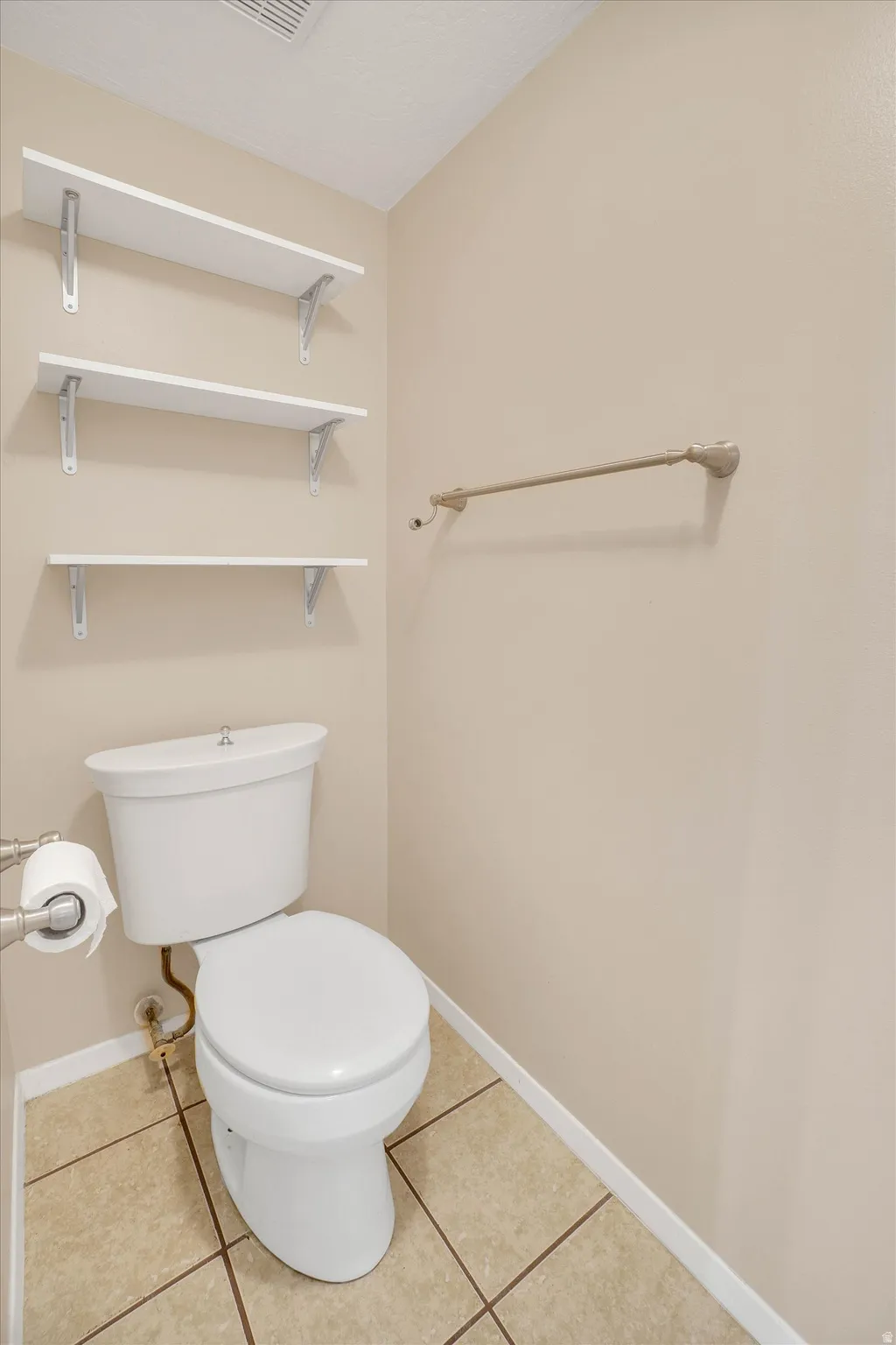 Built-in shelving, ceramic tile flooring, and a towel bar in master bathroom