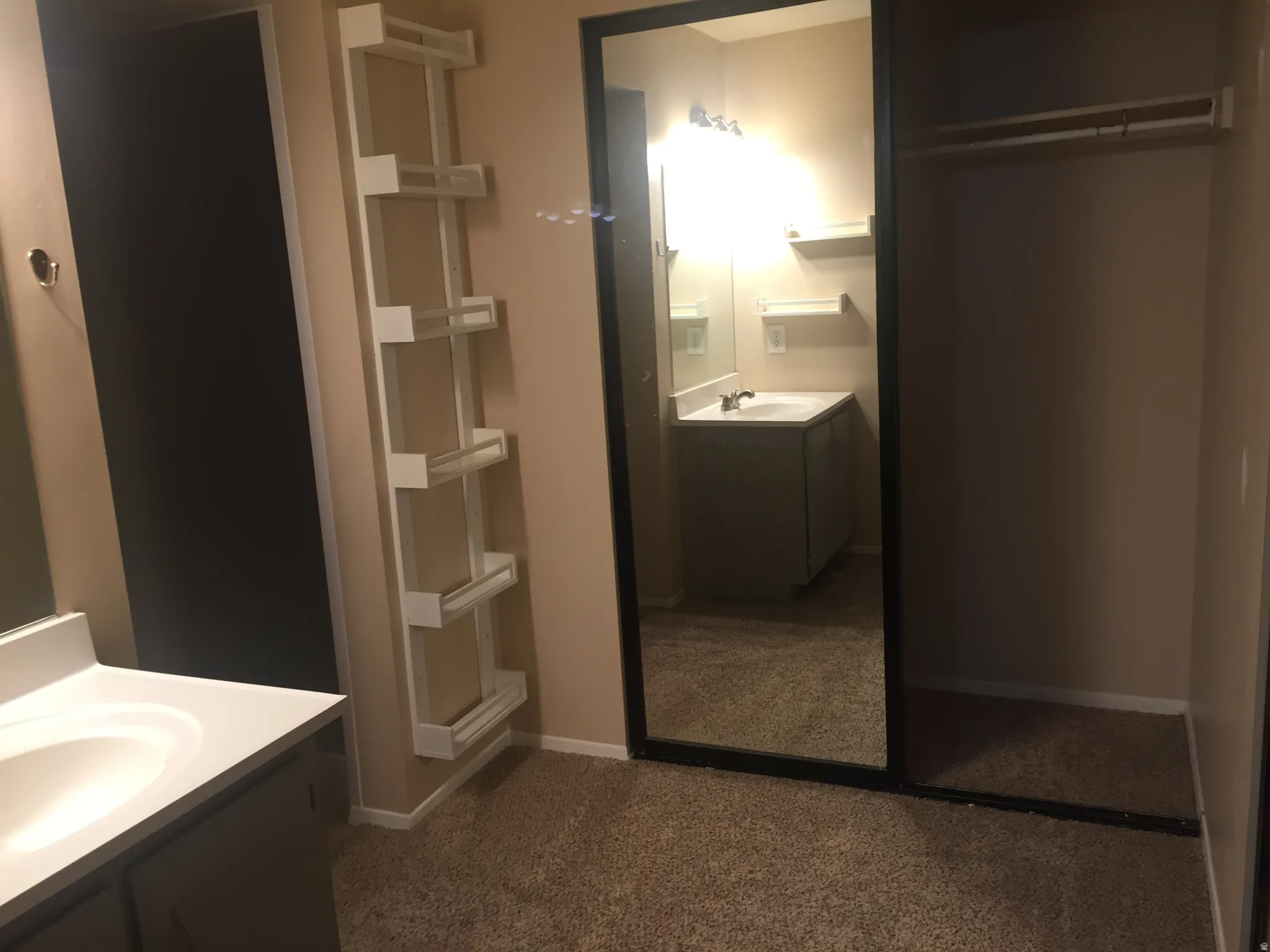 Carpeted room featuring a full-length mirrored sliding door and built-in white shelving